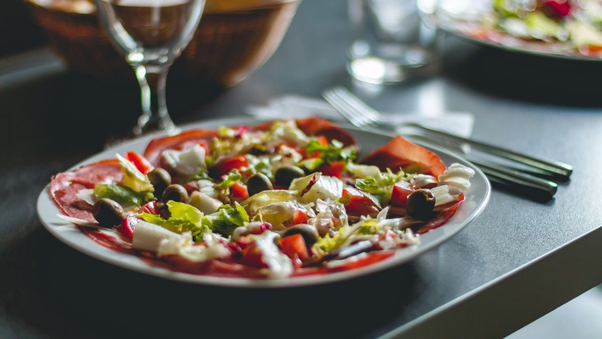 Enticing Mediterranean salad featuring olives, cheese, and fresh vegetables on a ceramic plate.